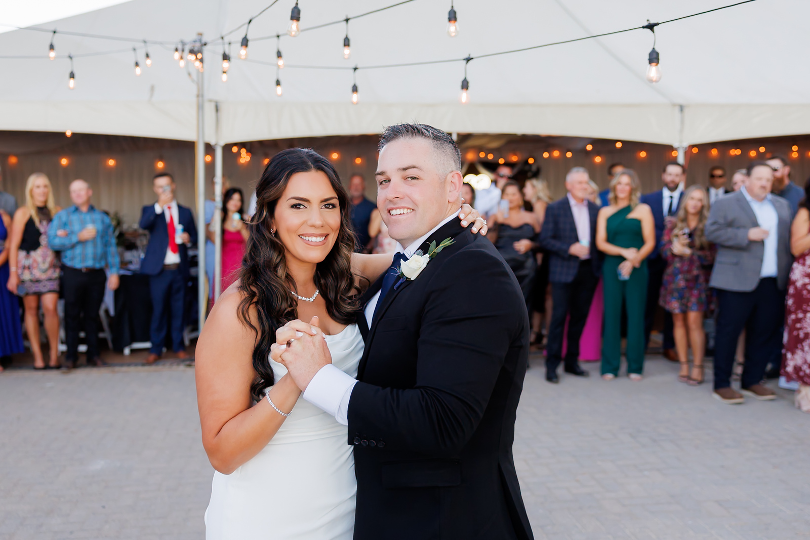 A couple toasting with guests at a warm outdoor wedding reception